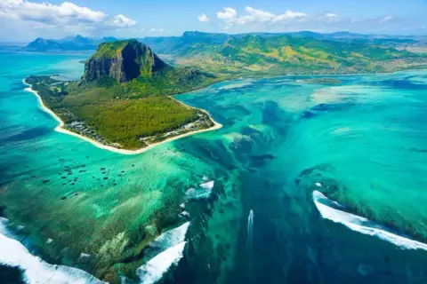 Widok z lotu ptaka na Le Morne Brabant, Mauritius, gdzie leży ta wyspa. Turkusowa woda, rafy koralowe i góra tworzą iluzję podwodnego wodospadu.