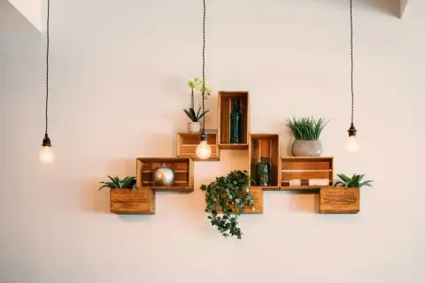Scaffali in legno a forma di cassa, decorati con piante e oggetti, mostrano come attaccare una mensola al muro con stile.