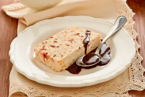 Delizioso semifreddo alla mandorla con salsa al cioccolato su un piatto bianco, pronto per essere gustato.