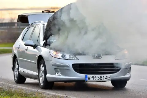 Srebrny Peugeot z otwartą maską, z której bucha dym. Rozbiegany silnik diesla dał o sobie znać w najgorszym momencie.