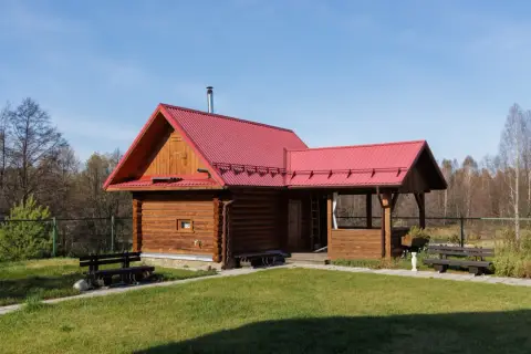 Drewniany domek z czerwoną dachem, idealny na wynajem. Możliwa dotacja na taki domek.