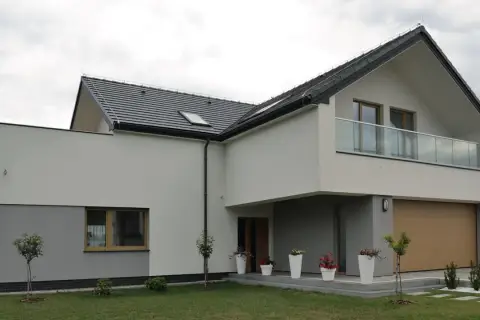 Nowoczesny dom z dwuspadowym dachem i balkonem. Ocieplenie domu wzory tynków w odcieniach bieli i szarości.
