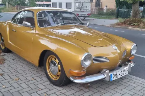 Złoty Karmann Ghia, klasyk z lat 60., lśni na tle ulicy.