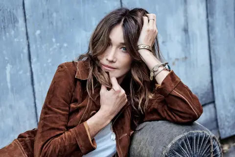 Carla Bruni joven, con su melena suelta y mirada penetrante, posa con una chaqueta de ante marrón.