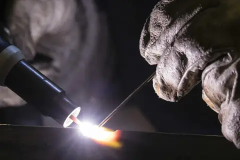 Un soldador usa una antorcha para crear una chispa brillante, demostrando que es la soldadura.