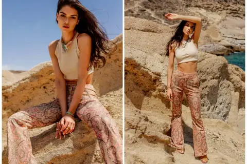 Modelka w beżowym topie i spodniach z orientalnym wzorem paisley, pozuje na tle skalistego krajobrazu.