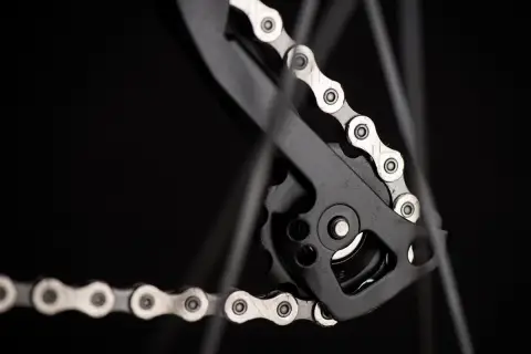 Zbliżenie na rowerowy napęd, gdzie widać mechanizm przerzutki i fragment łańcucha. Dowiedz się, jak liczyć ogniwa w łańcuchu, by zapewnić płynną jazdę.