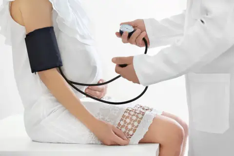 Lekarz mierzy ciśnienie ciężarnej pacjentce, monitorując jej stan przedrzucawkowy.