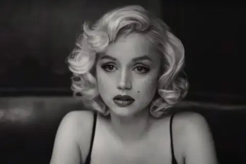 Kobieta w stylu Marilyn Monroe, z charakterystyczną fryzurą i makijażem, przypomina ikony z jej filmów.