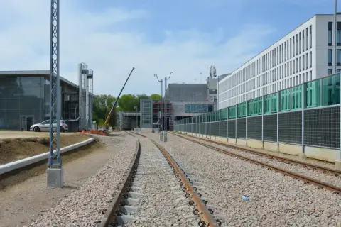 Budowa stacji Kraków-Balice PKP. Torowisko w budowie, nowoczesne budynki, dźwig.