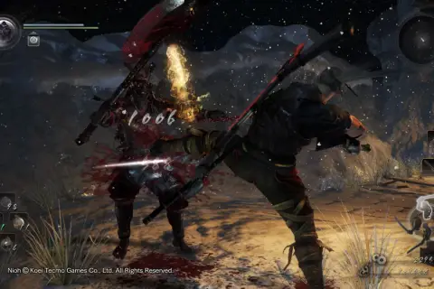 Intensywna walka w Nioh 2. Wojownik w czerwonej zbroi otrzymuje cios, z jego ciała tryska krew.