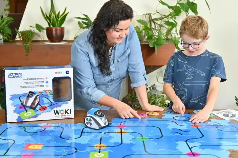 Mama i syn bawią się robotem WOKI, ucząc się kodowania dla 6 latka. Kolorowe klocki tworzą labirynt.