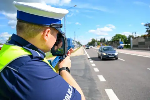 Policjant mierzy prędkość pojazdu, aby ustalić taryfikator punktów karnych.