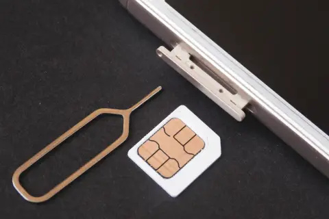 Narzędzie do otwierania tacki SIM i karta SIM obok telefonu. Dowiedz się, jak odblokować kartę SIM, aby móc korzystać z telefonu.