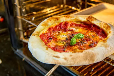 Heißer Pizzaofen: Eine Margherita-Pizza mit frischem Basilikum wird bei optimaler Pizzaofen Temperatur gebacken.
