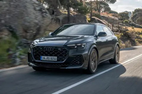 Czarny Audi RS Q8 pędzi po krętej drodze wśród skał i drzew. Sprawdź aktualną audi rsq8 cena!