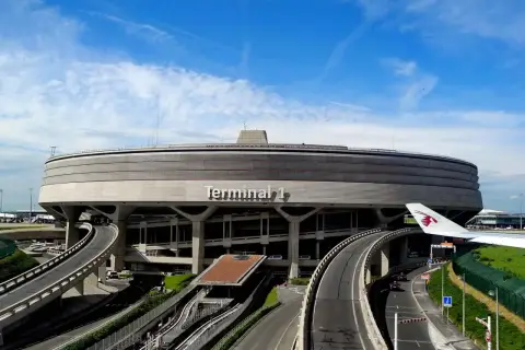 Terminal 1 na lotniskach w Paryżu, z charakterystyczną, okrągłą architekturą i wijącymi się drogami.