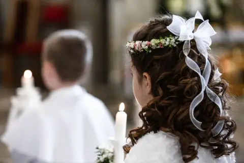 Dziewczynka z wiankiem i wstążkami we włosach trzyma świecę. Obok niej chłopiec. To ważny dzień, zastanawiasz się, ile trwa biały tydzień?