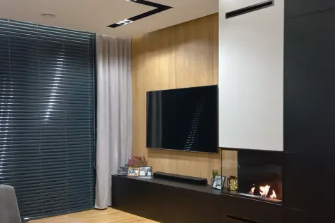 Nowoczesny salon z telewizorem i palącym się kominkiem bio do zabudowy.