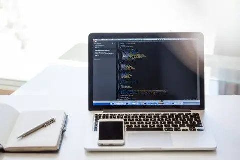 Laptop z kodem CSS, notatnik i telefon. Dowiedz się, jak zrobić listę numerowaną w HTML, tworząc strony internetowe.