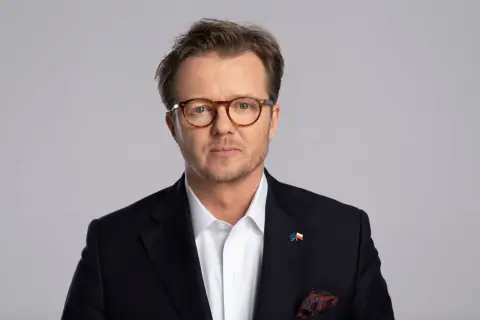 Michał Wawrykiewicz, prawnik i działacz społeczny, w garniturze z flagami UE i Polski. Jego życiorys to historia walki o prawa obywatelskie.