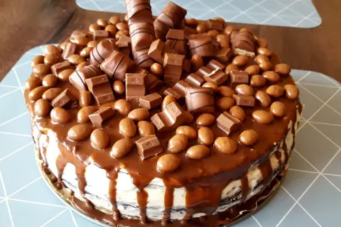 Pyszny tort kinder obficie udekorowany batonikami i czekoladowymi kuleczkami.