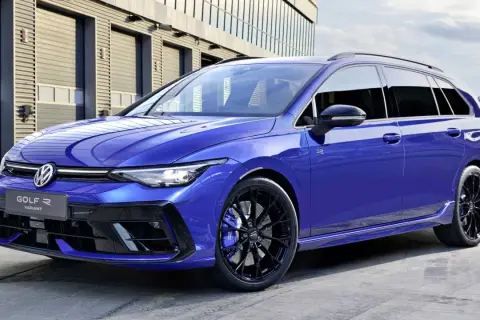 Niebieskie kombi auto Volkswagen Golf R Variant z czarnymi felgami i niebieskimi zaciskami hamulcowymi stoi przed nowoczesnym budynkiem.