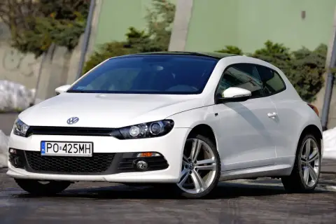 Biały Volkswagen Scirocco z czarnym dachem, zaparkowany na zewnątrz.