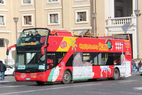 Un bus rouge à deux étages, un bus touristique "City Sightseeing Roma", circule dans la ville.