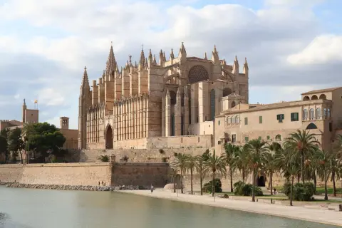 La Catedral de Mallorca, un impresionante edificio gótico, se alza majestuosa junto al mar, evocando la grandeza de Barcelona.