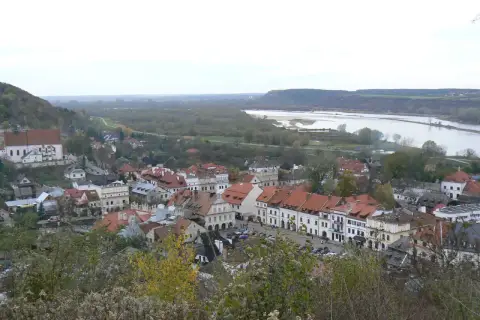 Widok na Kazimierz Dolny z rzeką Wisłą w tle. Planujesz podróż? Sprawdź, jak dojechać do Kazimierza Dolnego pociągiem.