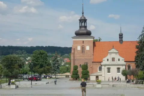Włocławek atrakcje na weekend: plac z katedrą, spacerowicze, drzewa i zielone wzgórza w tle.