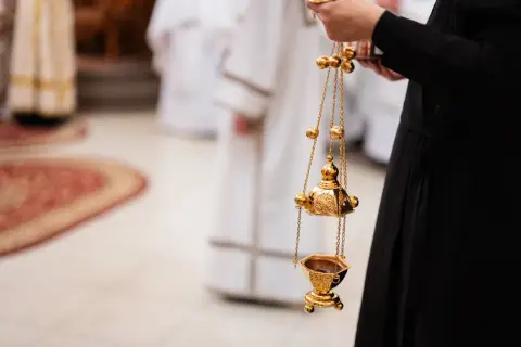 Złota kadzielnica w ręku osoby w czarnej szacie. Czy msza w środę popielcową jest obowiązkowa?
