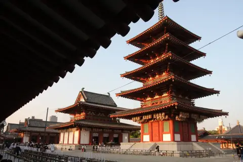 Pięciopiętrowa pagoda i inne budynki świątyni buddyjskiej w Japonii, z tradycyjnymi dachami i czerwonymi detalami.