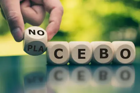 Palec odwraca kostkę z napisem "NO" na "PLACEBO", pokazując, czym jest efekt nocebo.