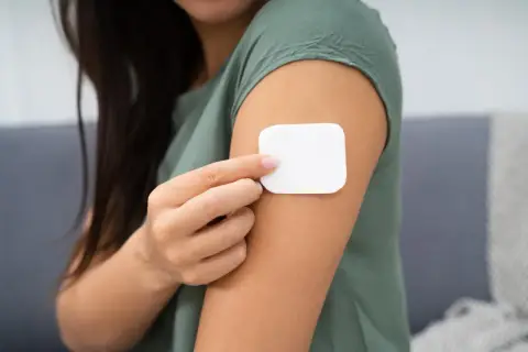 Kobieta przykleja plaster antykoncepcyjny. Przed użyciem warto zapoznać się z przeciwwskazaniami.