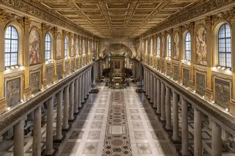 L'interno della Basilica di Santa Maria Maggiore a Roma, con il suo soffitto dorato, le colonne imponenti e i mosaici che narrano storie sacre.