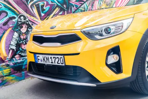 Żółty, stonic kia z pirackim graffiti w tle.