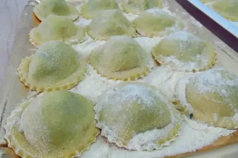 Ravioli verdi su vassoio, perfetti con cosa sostituire la ricotta nella dieta.