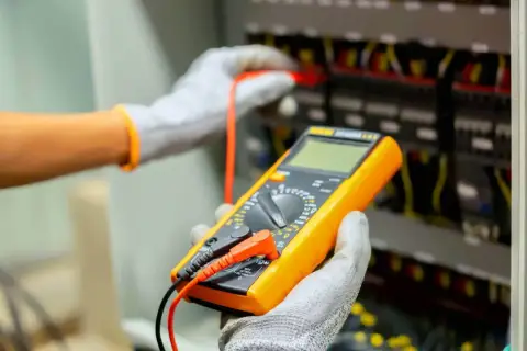 Elektryk z multimetrem wykonuje pomiary elektryczne. Sprawdź nasz cennik usług.