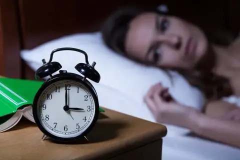 Kobieta nie może zasnąć, budzik pokazuje 3:00. Czy to melatonina skutki uboczne?