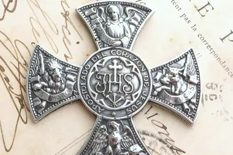 Srebrny medalion z symbolem IHS i symbolami ewangelistów: lew (św. Marek), anioł (św. Mateusz), wół (św. Łukasz) i orzeł (św. Jan).