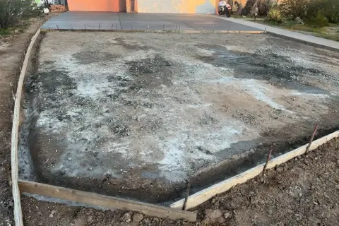 Plac budowy podjazdu z kamienia. Widać szalunki i przygotowany teren pod wylanie betonu.