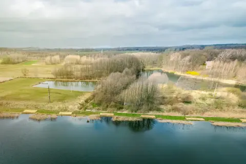 Krajobraz z jeziorami i lasem, gdzie widać ślady komercji w postaci przygotowanych miejsc nad wodą.