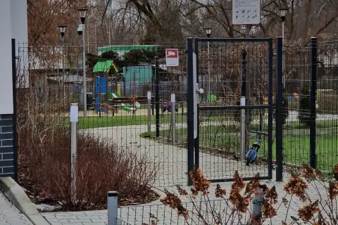 Prawda o ustawie która ma zakazać grodzenia osiedli w dużych miastach: ogrodzony plac zabaw z bramą i tablicą informacyjną.