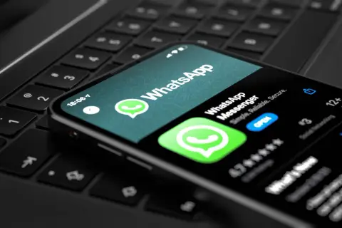 Telefon z aplikacją WhatsApp na klawiaturze laptopa. Wygodny sposób na korzystanie z WhatsApp na komputerze.