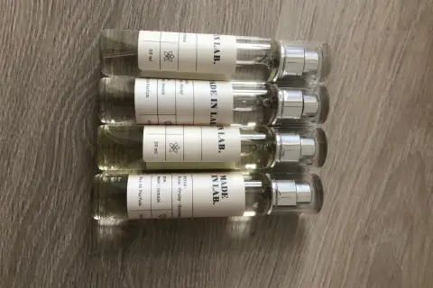Cztery małe flakoniki perfum "MADE IN LAB." na drewnianym tle. Opinie o nich są pozytywne, doceniane za zapachy.