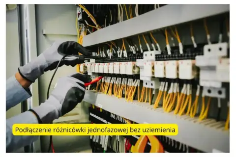 Ręce w rękawicach testujące instalację elektryczną z żółtymi przewodami.