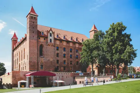 Zamek w Malborku, największe województwo w Polsce, z czerwonymi dachami i wieżami, otoczony zielenią i błękitnym niebem.