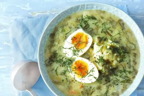 Zupa szczawiowa z jajkiem i koperkiem w misce, obok chochla.